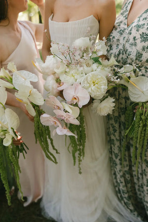 Bridesmaids holding bouquets with white and green flowers.