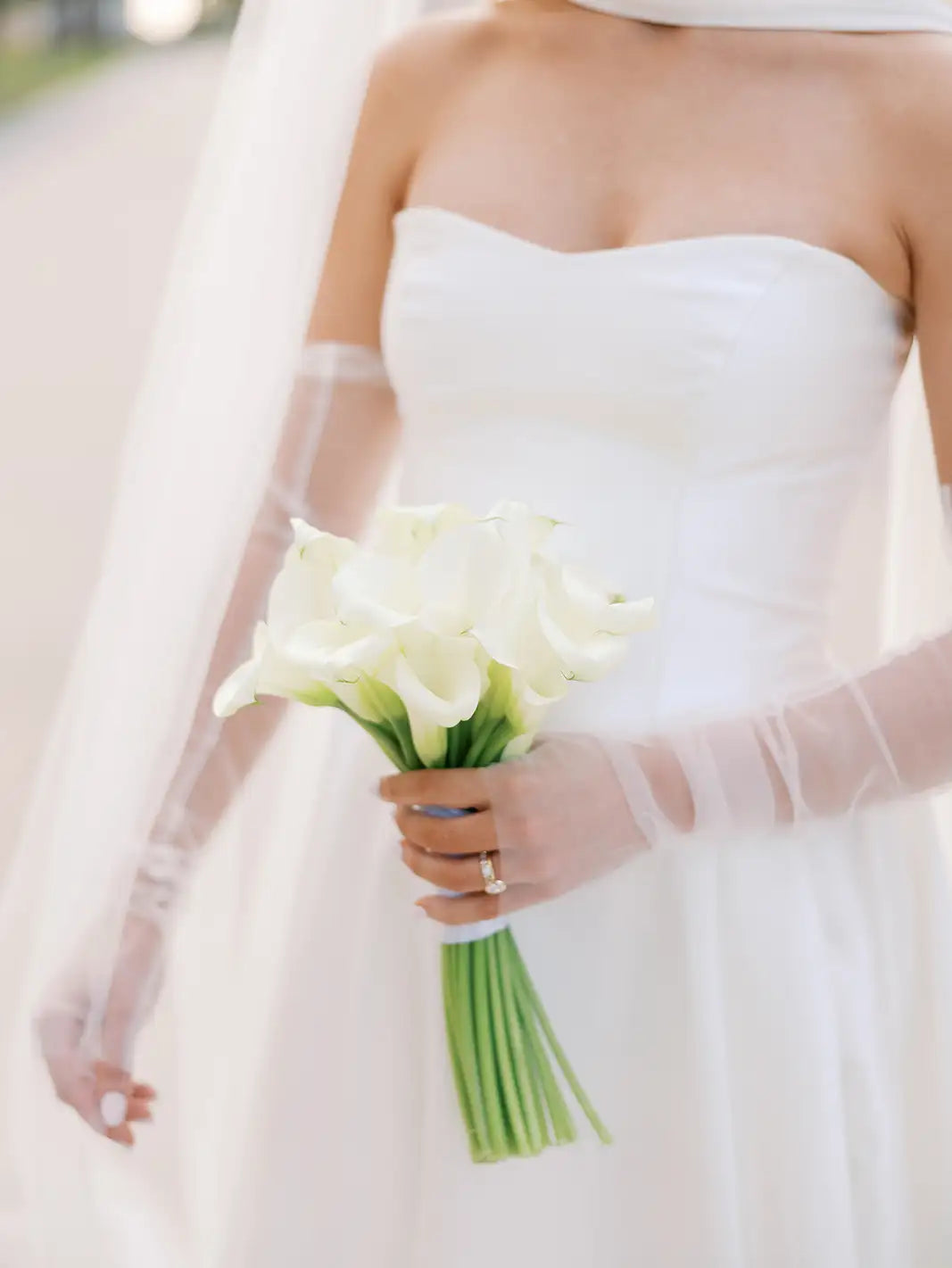 Bride holding a bouquet of white flowers with a blurred background