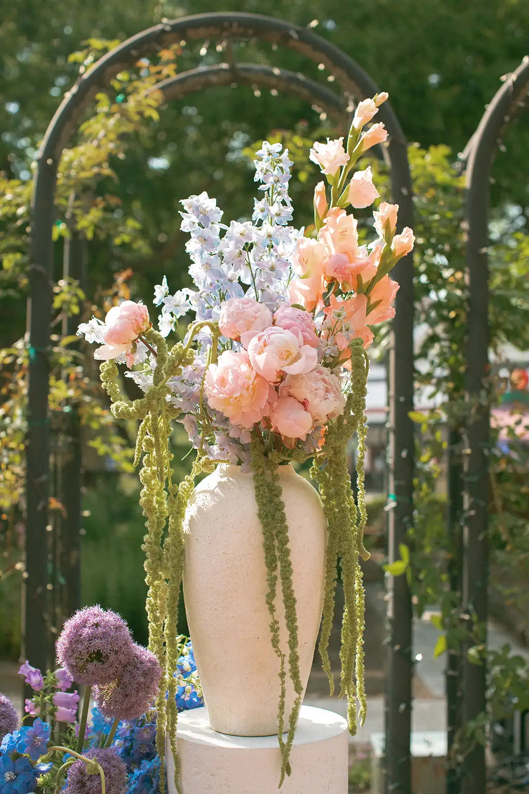Decorative floral arrangement in a white vase with a blurred garden background