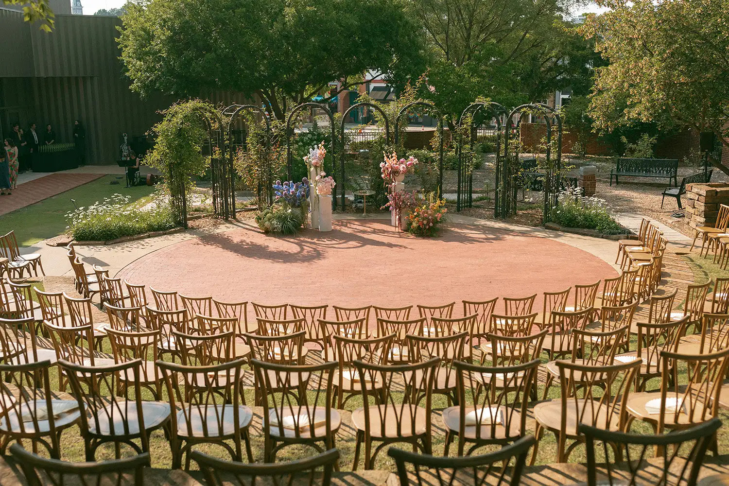 Outdoor wedding setup with chairs arranged in a circle, floral arches